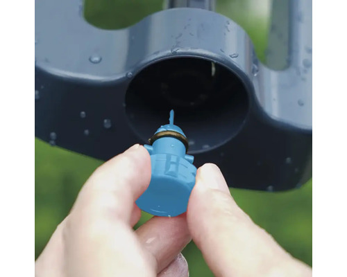 Detailaufnahme einer Hand, die eine Düse in einen Rasensprenger einsetzt.