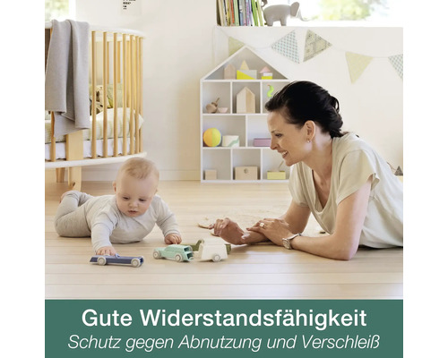 Baby und Frau spielen mit Spielzeugautos auf einem hellen Holzboden in einem hellen Kinderzimmer mit Gitterbett und Hausregal.
