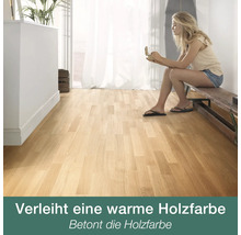 Heller Wohnraum mit Parkett in warmer Holzfarbe, auf dem eine Frau auf einer Holzbank sitzt.