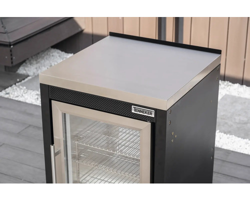 Tenneker Outdoor-Kühlschrank Modul mit Arbeitsplatte aus Edelstahl und Glastür in einer hellen Außenküche auf einer Terrasse.