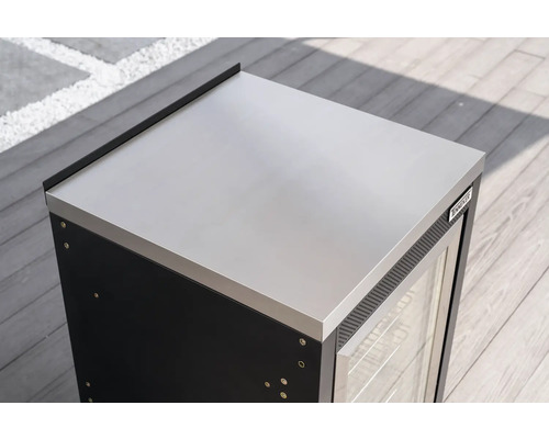 Tenneker Außenküchen-Modul mit Edelstahlarbeitsplatte, Glastür und Tenneker Logo auf einer Holzterrasse.