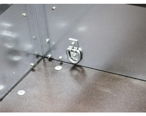 Zurröse aus Metall montiert an der Seitenwand eines Anhängers mit strukturiertem Boden.