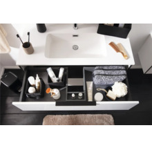 Moderner weißer Waschtisch mit geöffneter Lade, Organisationssystem für Laden mit Toilettenartikeln und hellbraune Badematte.