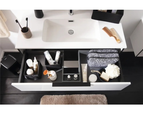 Moderner weißer Waschtisch mit geöffneter Lade, Organisationssystem für Laden mit Toilettenartikeln und hellbraune Badematte.