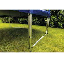 Nahaufnahme eines Trampolingestells mit U-förmigen Metallfüßen auf einer Rasenfläche im Garten.