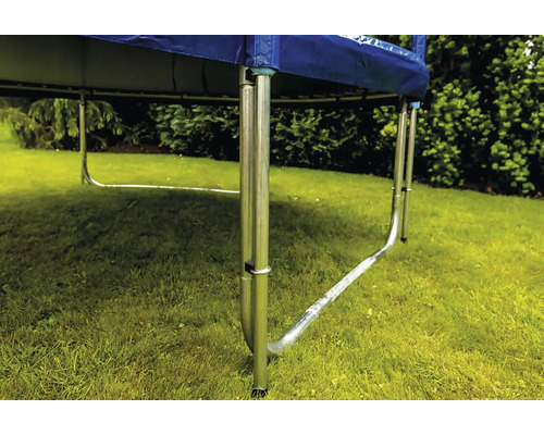 Nahaufnahme eines Trampolingestells mit U-förmigen Metallfüßen auf einer Rasenfläche im Garten.