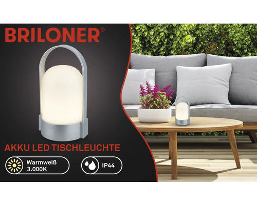 Briloner Logo, Akku LED Tischleuchte, warmweiß 3000 Kelvin, IP44 spritzwassergeschützt, tragbar mit Tragegriff, im Garten auf einem Holztisch.