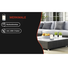 Tragbare Leuchte auf einem weißen Tisch in einem hellen Loungebereich mit Korbmöbeln. Merkmale: Stufendimmbar und inklusive USB-C-Kabel.