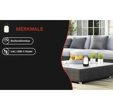 Stufendimmbare LED-Leuchte inklusive USB-C-Kabel auf einem Rattan-Gartentisch mit Obst und Pflanzen vor einer hellen Lounge.