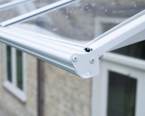 Detail einer weißen Terrassenüberdachung aus Aluminium mit transparenten Paneelen.
