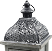 Nahaufnahme einer dekorativen Laterne mit Holzsockel und verziertem Metalldach mit Lochmuster sowie einem Ring zum Aufhängen.