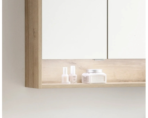 Badezimmer-Spiegelschrank mit offenem Ablagefach in Holzoptik, auf dem Pflegeprodukte stehen.
