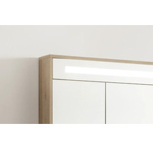 Obere Ecke eines Badezimmerschranks mit Korpus in Eichenoptik, weißer Front und integrierter LED-Beleuchtung.