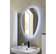 Asymmetrischer LED-Badspiegel über einem weißen Waschbecken mit schwarzer Armatur in einem modern gestalteten Badezimmer.