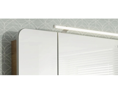 Spiegelschrank mit LED-Aufsatzleuchte und Korpus in Holzoptik.