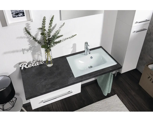 Helles Badezimmer mit weißem Unterschrank, dunkler Arbeitsplatte in Steinoptik und integriertem weißem Waschbecken mit verchromter Armatur.