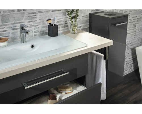 Moderner Waschtisch mit Glaswaschbecken, anthrazitfarbenem Unterschrank und passendem Hochschrank vor einer Wand in Steinoptik.