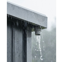 Detailansicht eines Regenwasserablaufs an einem Metallgartenhaus bei Regen mit fließendem Wasser.