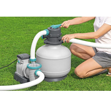 Sandfilteranlage für Pools mit Pumpe und Schläuchen bei der Bedienung auf einer Rasenfläche.