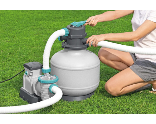 Sandfilteranlage für Pools mit Pumpe und Schläuchen bei der Bedienung auf einer Rasenfläche.
