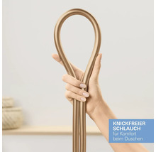 Hand hält einen goldfarbenen, knickfreien Brauseschlauch, der zu einer Schlaufe gebogen ist.