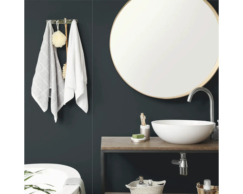 Modernes Badezimmer mit rundem Wandspiegel, weiem Aufsatzwaschbecken auf einer Holzplatte und Handtuchhalter.