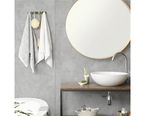 Modernes Badezimmer mit rundem Spiegel, weißer Waschschale auf einem Waschtisch in Holzoptik und grauer Wand in Betonoptik.