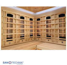 Innenansicht einer Infrarotkabine mit Holzbänken und Infrarotstrahlern hinter Holzgittern, Sanotechnik International Logo.
