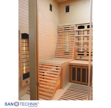 Innenansicht einer Infrarotkabine aus hellem Holz mit einer ergonomischen Holzliege, einer Sitzbank und Infrarotstrahlern.