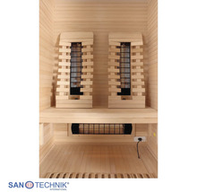Innenansicht einer hellen Infrarotkabine aus Holz mit zwei Rückenlehnen, Infrarotstrahlern und einer Sitzbank. Sanotechnik International Logo.