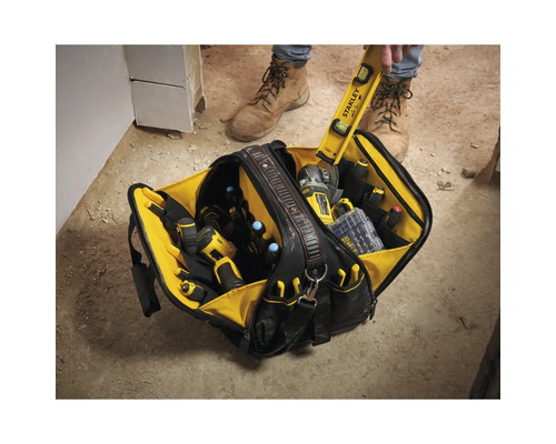 Offene Werkzeugtasche mit verschiedenen Hand- und Elektrowerkzeugen in mehreren Fächern auf einer Baustelle.