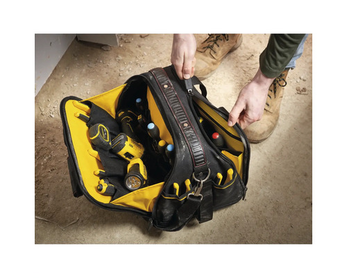 Person öffnet eine robuste Werkzeugtasche mit vielen Fächern, gefüllt mit Bohrschrauber, Taschenlampe und Schraubendrehern auf einer Baustelle.