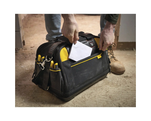 Handwerker nutzt die praktischen Außentaschen einer Stanley FatMax Werkzeugtasche aus robustem Gewebe auf einer Baustelle.