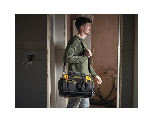 Handwerker trägt eine Stanley FatMax Werkzeugtasche mit Schultergurt auf einer Baustelle. Die Tasche verfügt über mehrere Außentaschen.