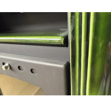 Detailansicht eines Kaminofens mit grüner Keramikverkleidung und mattschwarzem Metallgehäuse