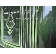 Detailansicht einer glänzenden Kachelofenverkleidung mit Relief und Rissoptik