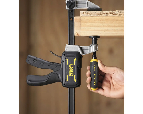 Stanley FatMax Einhandzwinge fixiert ein Holzbrett durch Betätigung des Schraubgriffs.