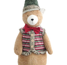Plüsch-Teddybär mit grüner Zipfelmütze, roter Fliege und gemusterter Weste mit Knöpfen.