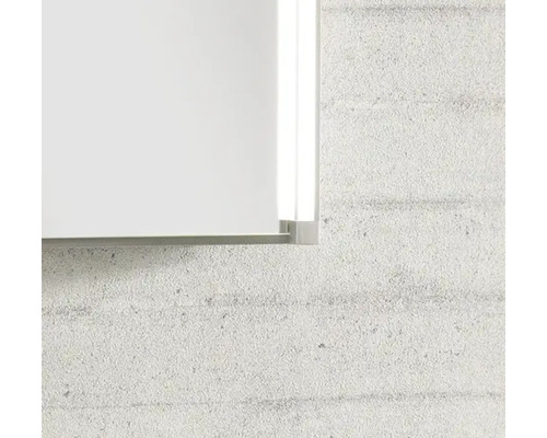 Detailaufnahme der Ecke eines Spiegels mit Metallrahmen und integrierter LED-Seitenbeleuchtung an einer strukturierten Wand.