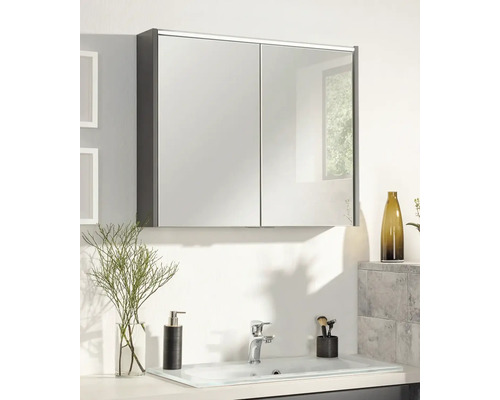 Zweitüriger Spiegelschrank über einem hellen Waschbecken in einem modern eingerichteten Badezimmer mit Seifenspender und Armatur.