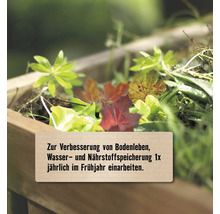 Gartenabfälle zur Bodenverbesserung in einem Holzbeet mit dem Hinweis, diese einmal jährlich im Frühjahr einzuarbeiten.