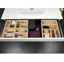 Organisierte Badezimmerschublade mit modularen Einsätzen aus hellem Holz für verschiedene Pflegeprodukte und Kosmetikartikel.