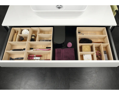 Organisierte Badezimmerschublade mit modularen Einsätzen aus hellem Holz für verschiedene Pflegeprodukte und Kosmetikartikel.