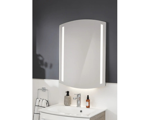 Badezimmerspiegel mit LED-Beleuchtung an den Seiten und unten, gewölbte Form, montiert über einem Waschbecken in einem modernen Badezimmer.