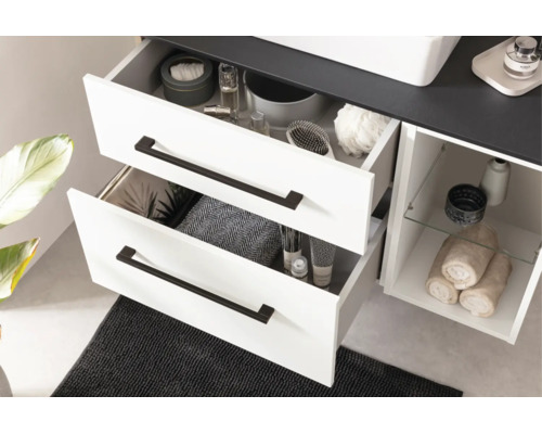 Weißer Badezimmer-Unterschrank mit zwei geöffneten Schubladen, schwarzen Griffen, offener Seitenablage mit Glasboden und dunkler Deckplatte.