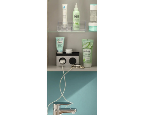 Organisierte Badschrank-Innenseite mit Regalböden für Pflegeprodukte, integrierter Steckdose mit Ladekabel und einer verchromten Armatur.