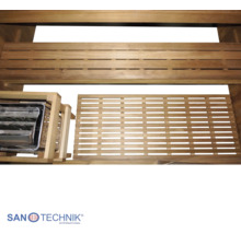 Saunainnenraum mit Holzbänken, einem hölzernen Bodenrost und einem Saunaofen in einer Schutzumrandung aus Holz. Sanotechnik International Logo.