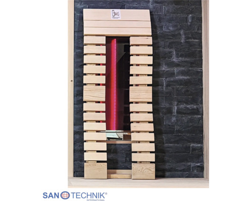 Infrarot-Saunastrahler mit rot leuchtender Lampe, eingefasst in helle Holzlamellen vor einer dunklen Steinwand. Sanotechnik International Logo.