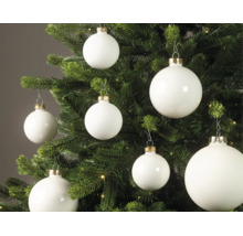 Weiße Christbaumkugeln in matter und glänzender Optik an einem grünen Tannenbaum mit kleinen Lichtern.