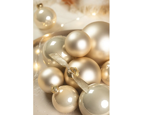 Arrangement von Weihnachtsbaumkugeln mit matten und glänzenden Oberflächen, eine mit einer dekorativen Schleife.